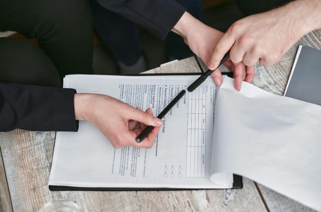 pexels-photo-7735699-7735699 Close-up of business hands finalizing agreement with pen on documents.